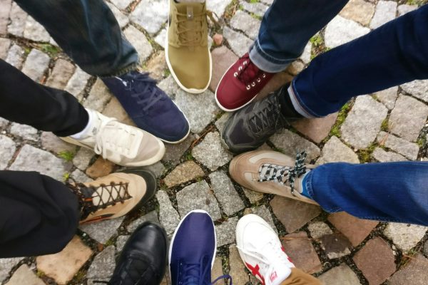 Circle of sneakers on cobblestone pavement representing diversity and urban fashion.